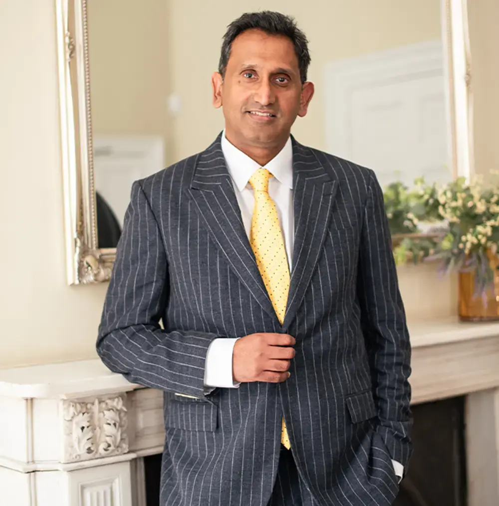 Professor Prasanna Sooriakumaran standing in a pinstripe suit and yellow tie